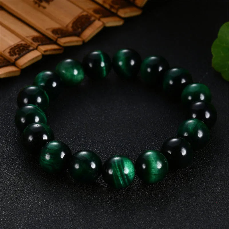 Polished green tiger eye stone bead bracelet with geometric beads on a wrist.