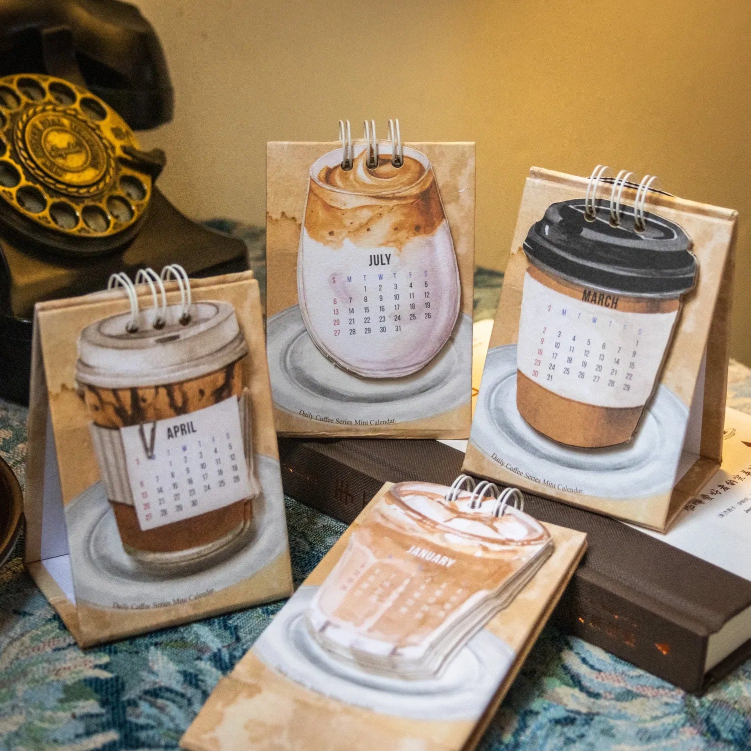 Mini A6 paper desk calendar for 2025 open to a monthly page with coffee-themed design.
