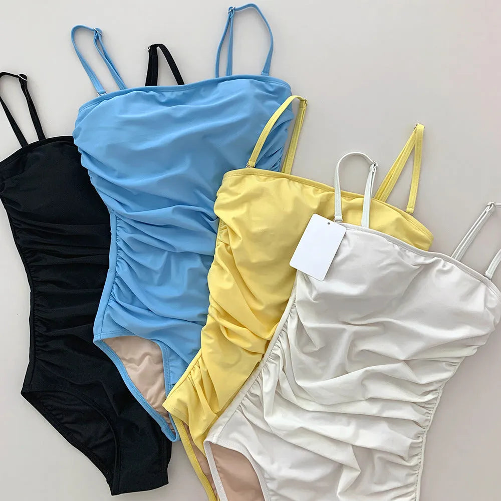 Blue sling style one-piece swimsuit with belly pleats on a mannequin, showing slim-fit design