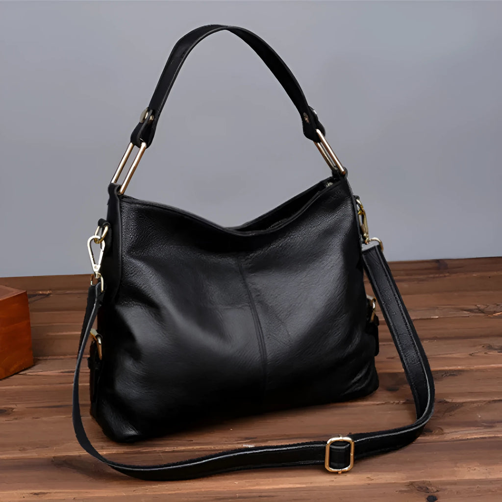 Genuine leather vertical square crossbody bag in black showing outer pocket and structured shape.
