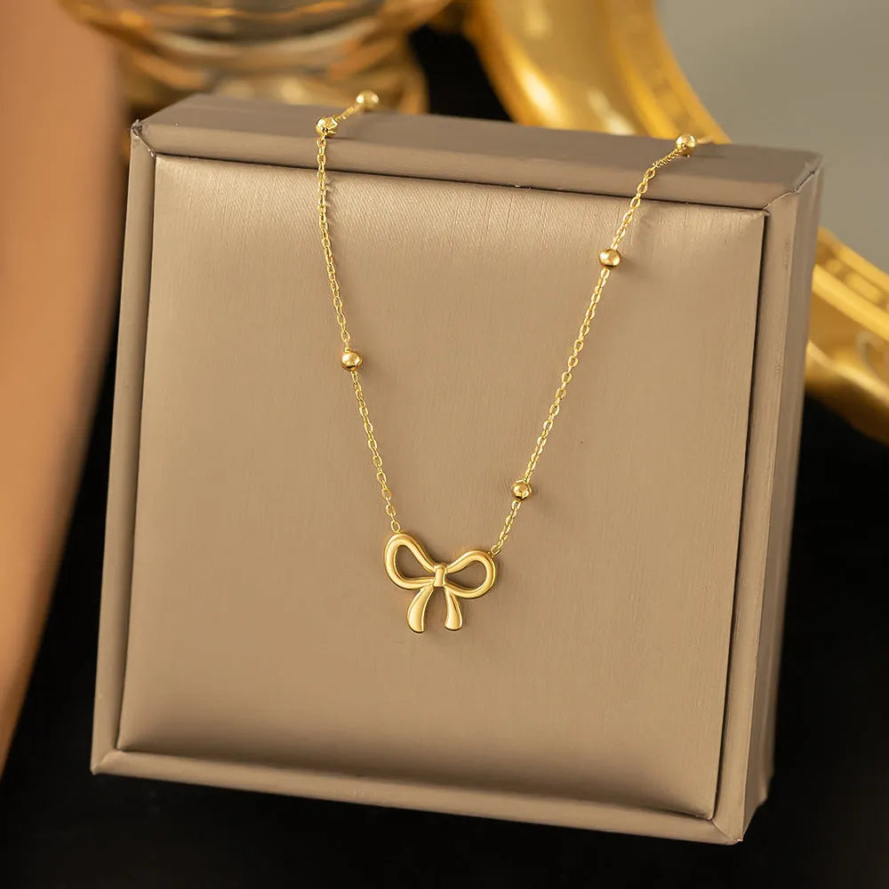 Gold electroplated titanium steel women's necklace with bow pendant and adjustable cross chain