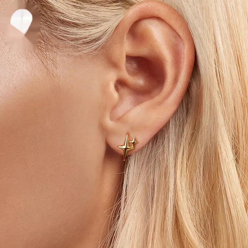 Minimalist oxidised sterling silver star clip-on earrings with XINGX detail on a white background.