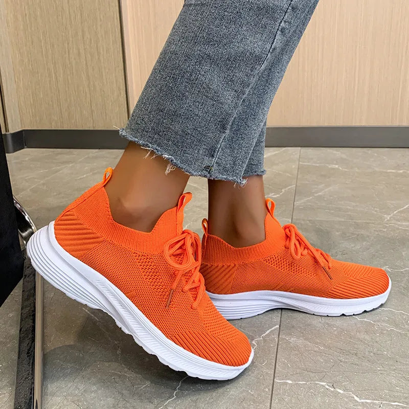Women's low-top running shoes with mesh lining and Flyknit upper in creamy white, grey, or orange colours