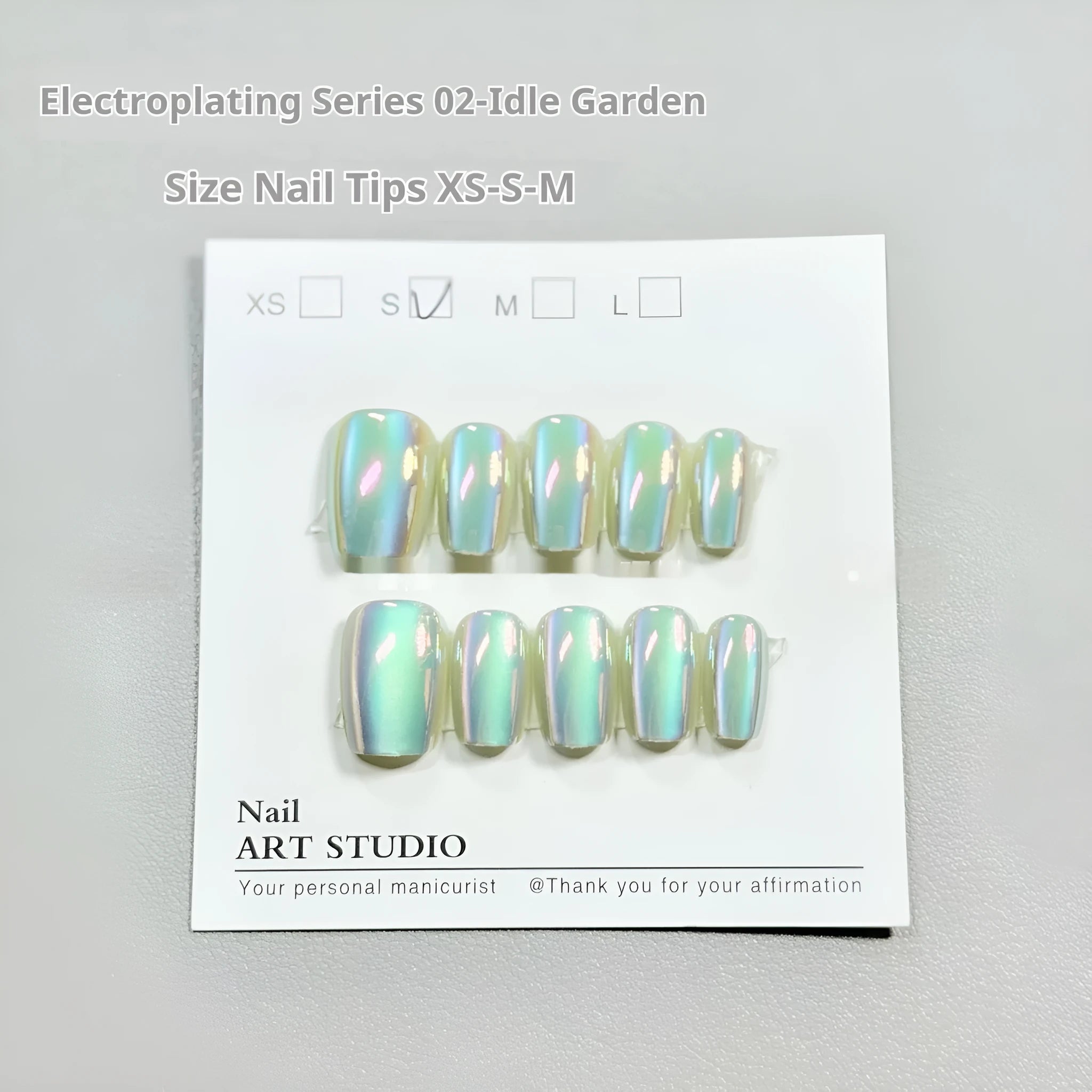 Electroplated cat's eye false nails with aurora colours in short ladder lengths on a hand.