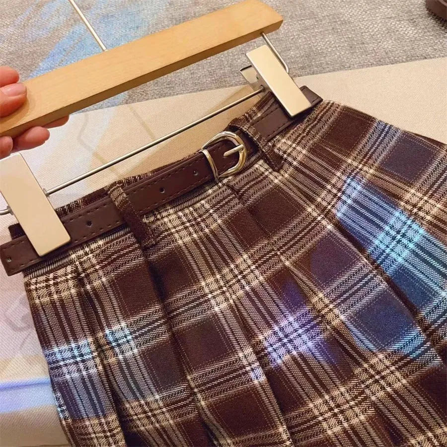 Girls plaid pattern pleated A-line skirt in cotton blend fabric on a hanger.