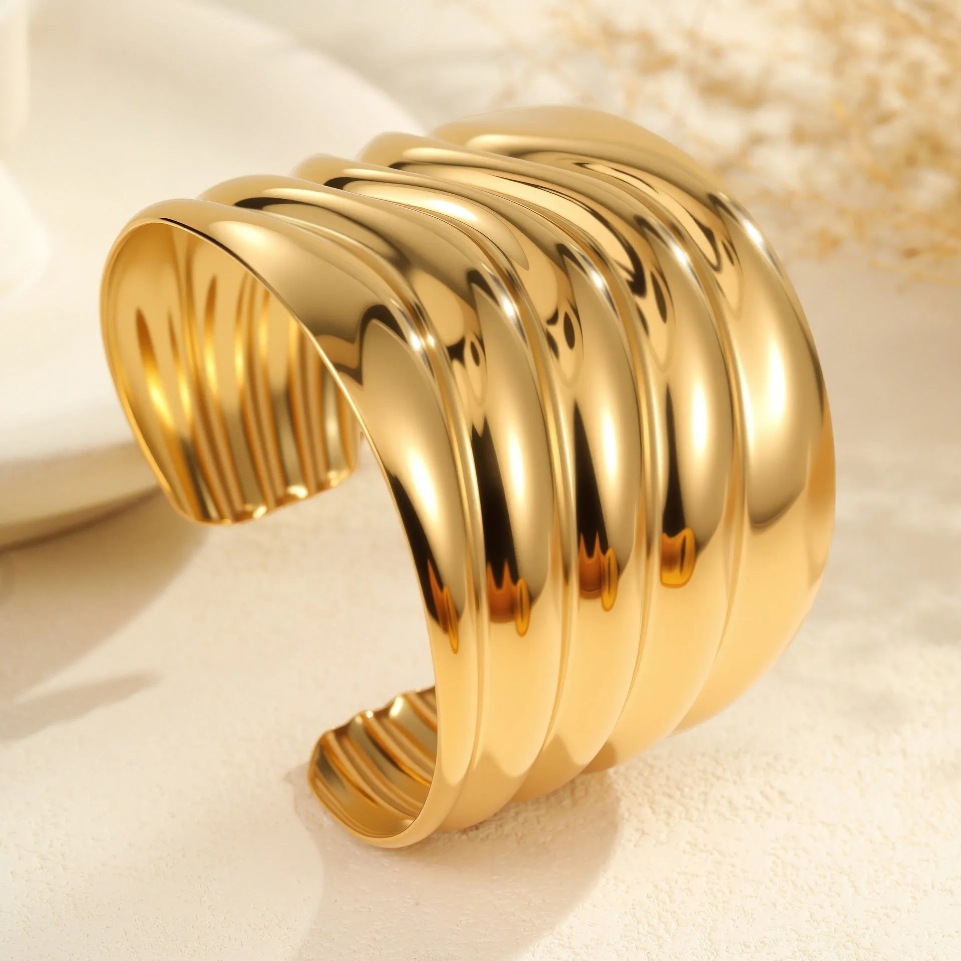 Women's wide stainless steel bracelet with 18K gold plating showing geometric wave patterns