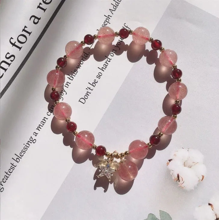Handcrafted strawberry quartz crystal bracelet with peach blossom design on wrist