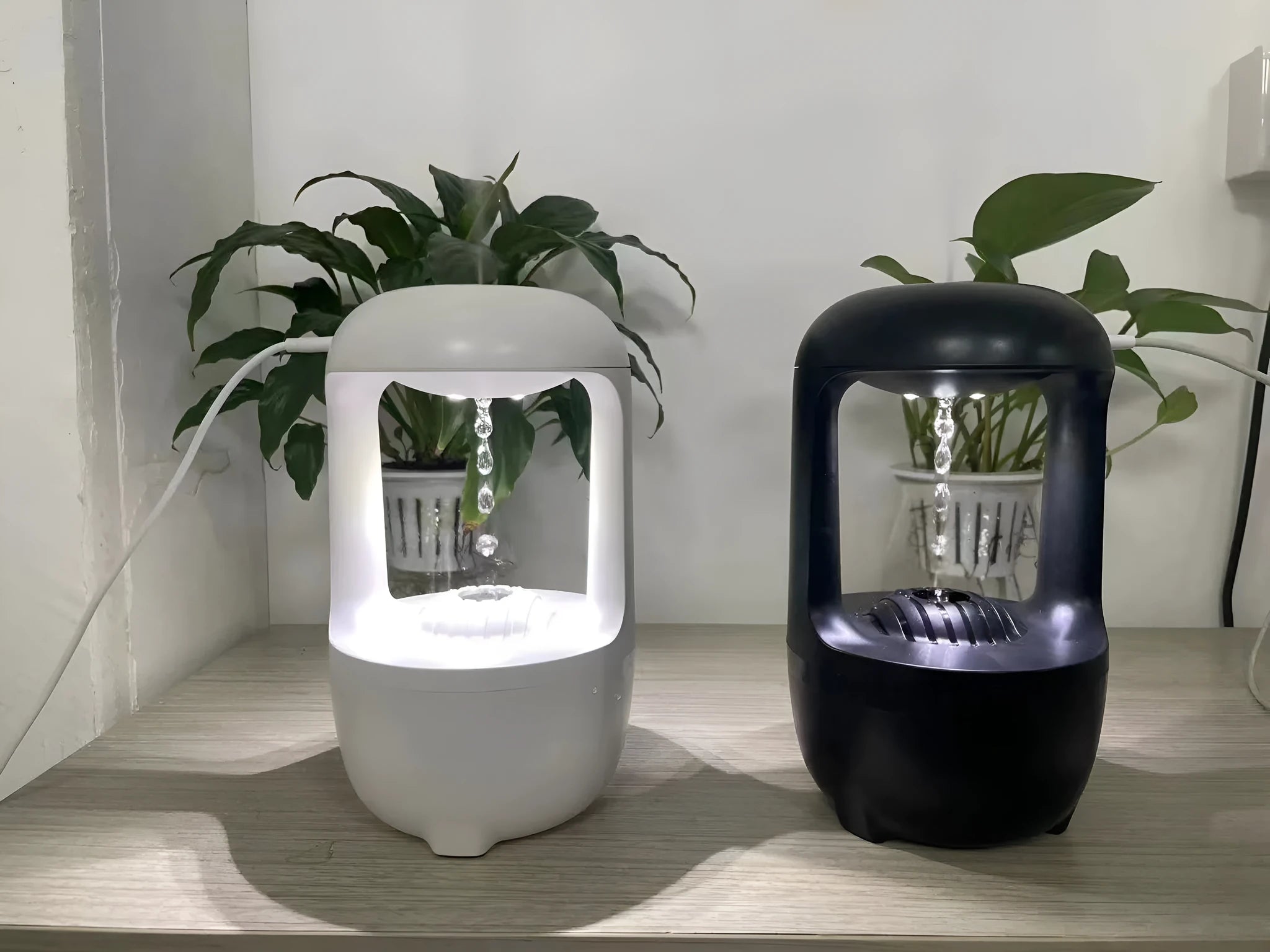 Black or white anti-gravity humidifier with water droplet effect on a desk.