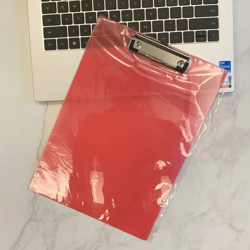 A4 transparent plastic writing board pad with metal clip in blue colour on a desk