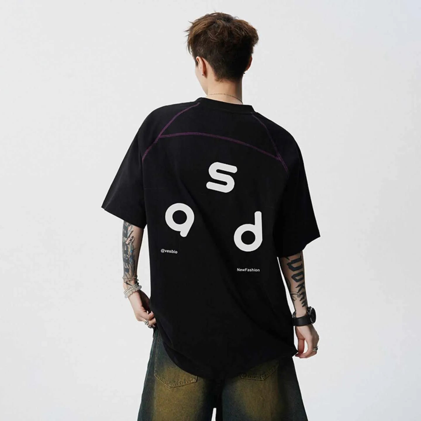 Man wearing a black loose-fit cotton T-shirt with a letter print on the chest.