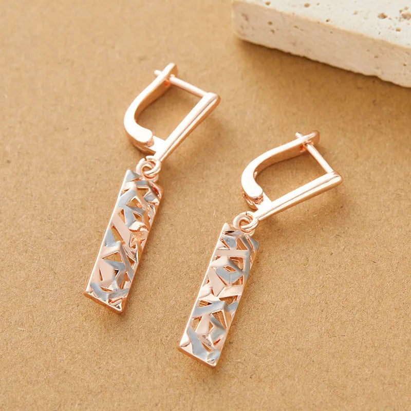A pair of rectangular hollow stud earrings with a two-tone geometric design on a white background.