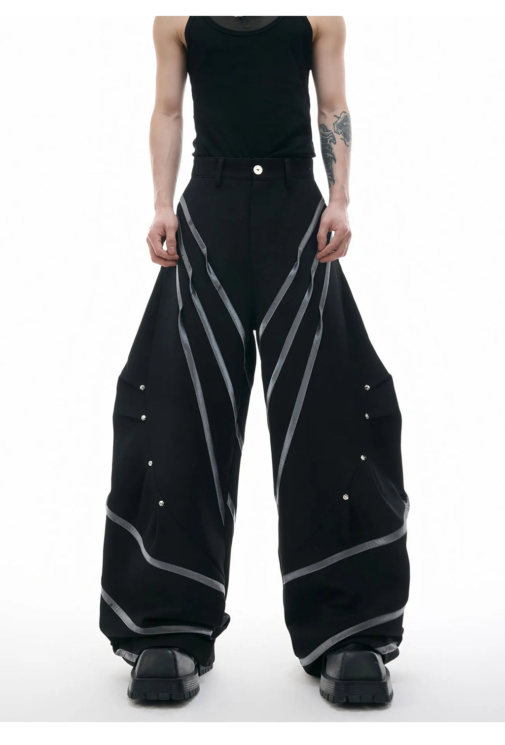 Men's black polyester trousers with front pleats and metal striped rivet details.
