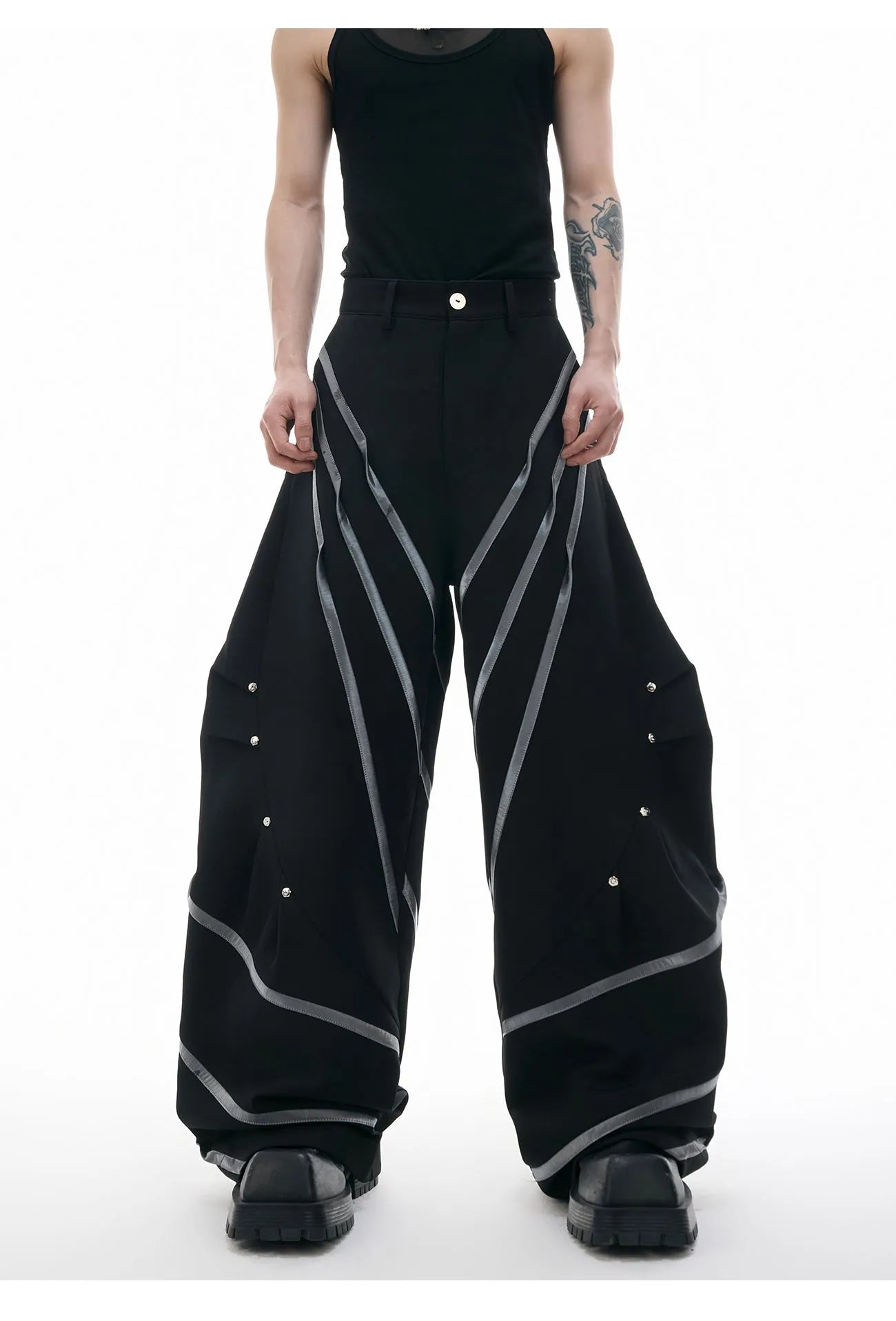 Men's black polyester trousers with front pleats and metal striped rivet details.