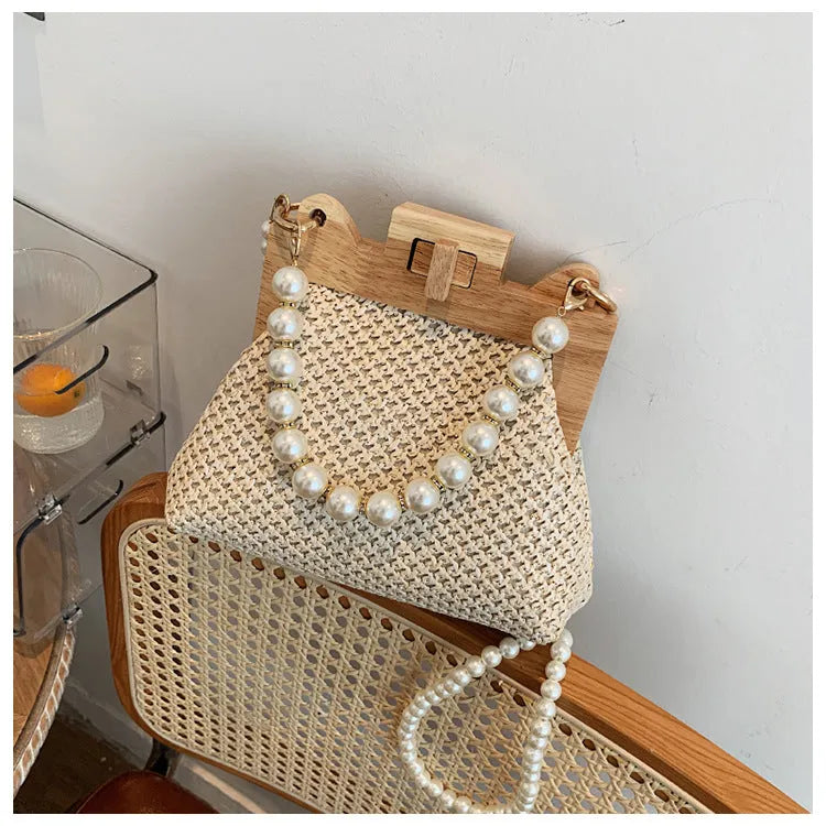 Women's straw woven shoulder bag with pearl chain detail showing internal organisation compartments