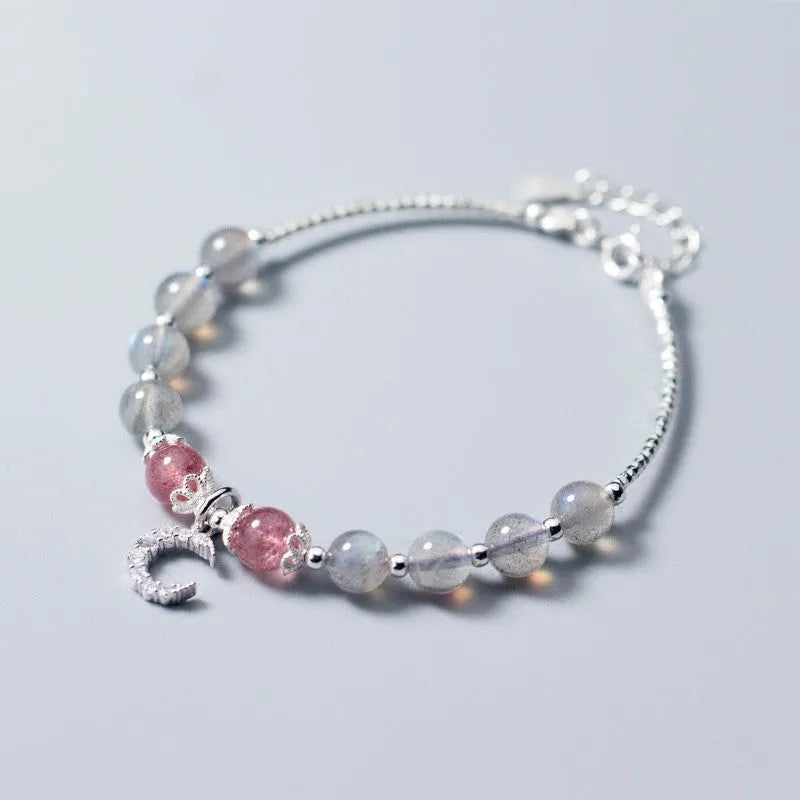 Simple handmade bracelet with round moonstone beads, a small crescent moon charm, and an adjustable metal clasp.