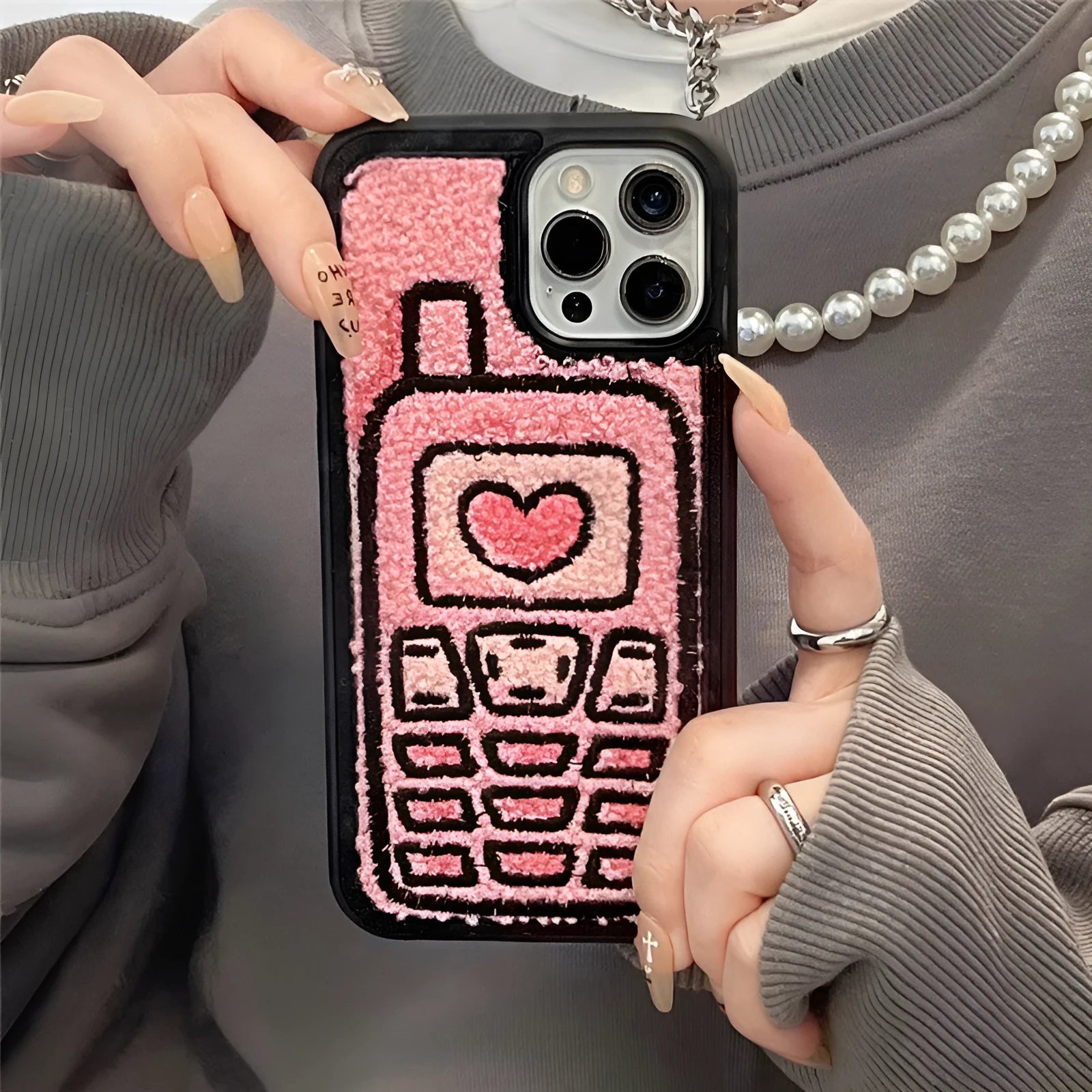 Pink TPU iPhone case with a towel-embroidered pattern, shown fitting an iPhone model.