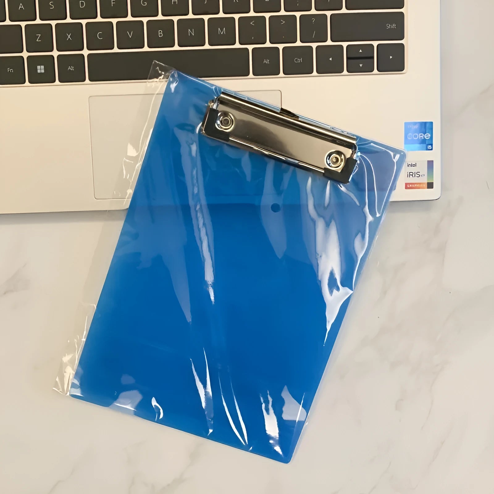 A4 transparent plastic writing board pad with metal clip in blue colour on a desk