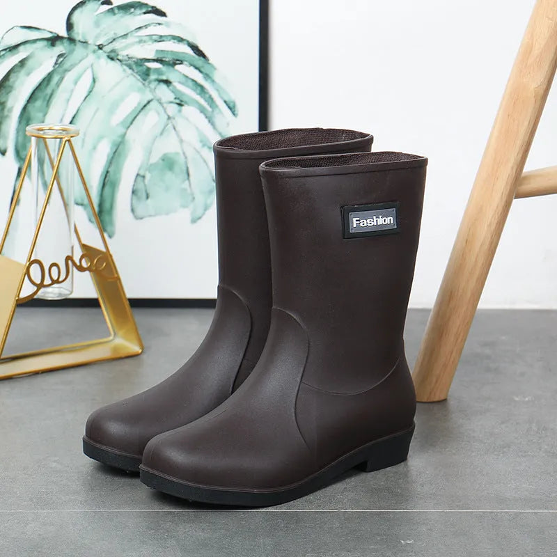 Women's mid-calf PVC rain boot in black on a wet surface.