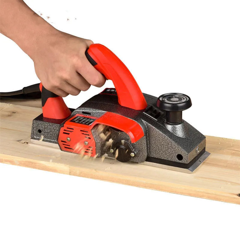 Red aluminium shell electric wood planer tool with 82mm planing width on a workbench.