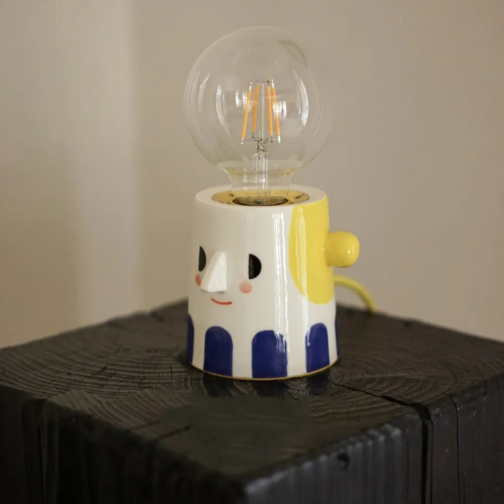 Handmade ceramic table lamp with a ball-shaped headlight on a neutral background.