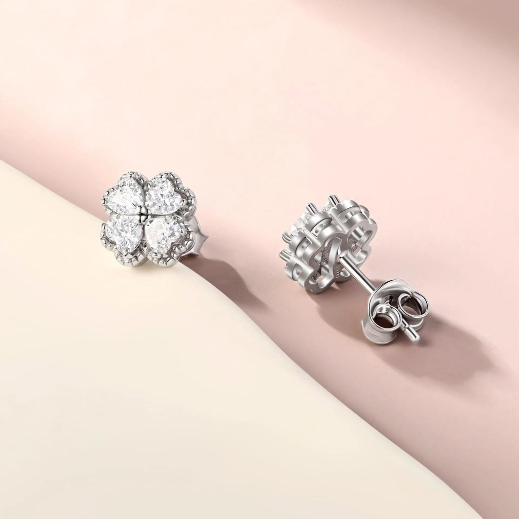 Close-up of women's 925 silver earrings with a four-leaf clover and heart design, inlaid with zircon stones in white gold colour.