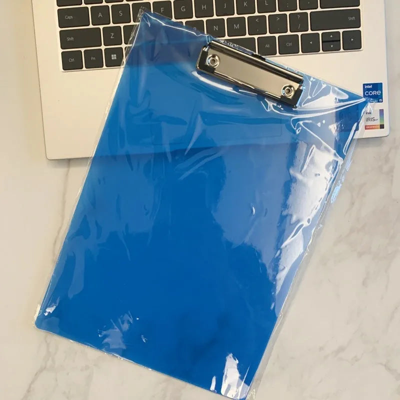 A4 transparent plastic writing board pad with metal clip in blue colour on a desk