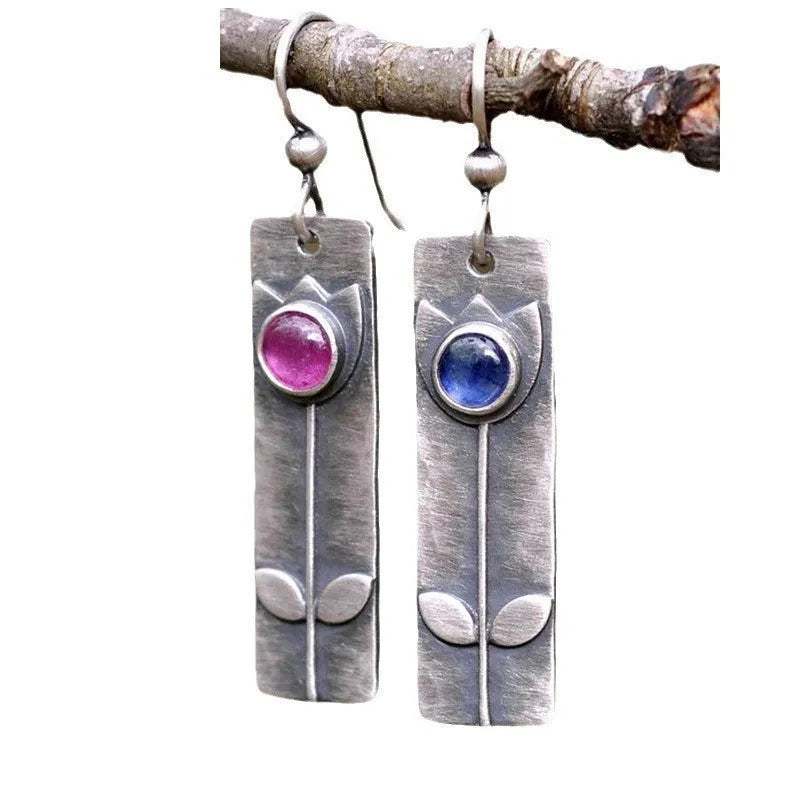 A pair of red sapphire earrings with an antique finish and geometric elliptical shape.