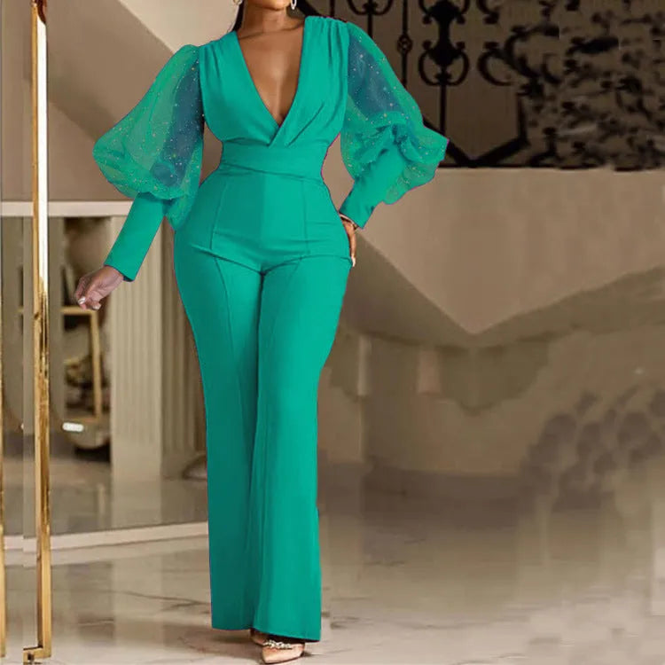 Red women's jumpsuit with mesh stitching on the torso, long sleeves, elastic waist, and wide-leg trousers.