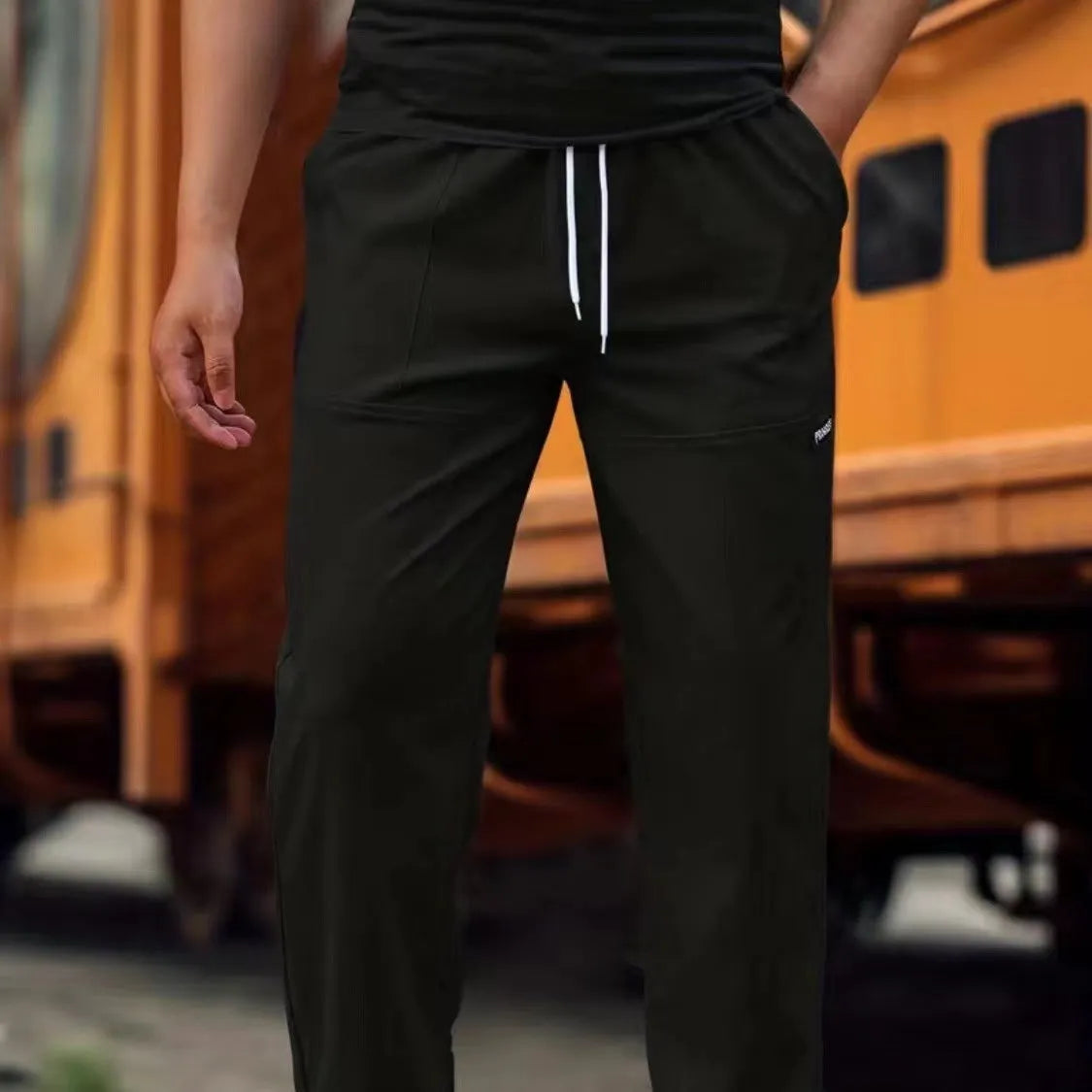 Men's polyester trousers in light grey, shown laid flat, suitable for spring and autumn wear.