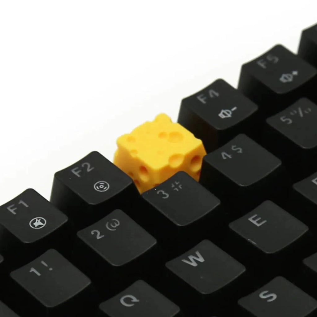 Yellow resin mechanical keyboard keycap shaped like a cheese wedge with a cute character face.