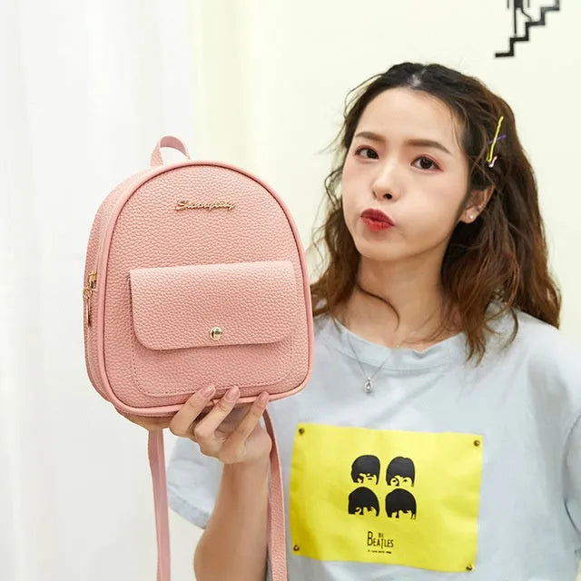 Small black PU shoulder backpack for women with zipper, shown next to a mobile phone for scale.