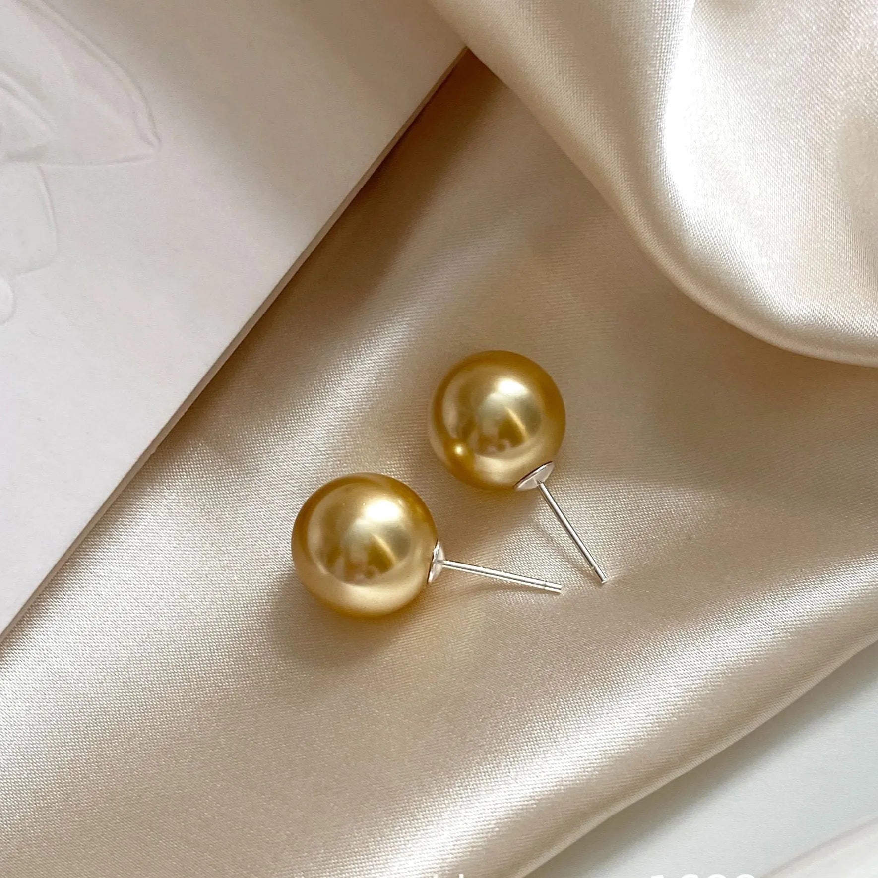 Geometric pearl stud earrings with an eight-point star setting, shown in silver.