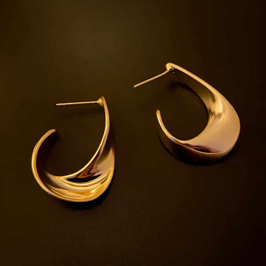 A pair of round, twisted geometric metal earrings with a gold electroplated finish.