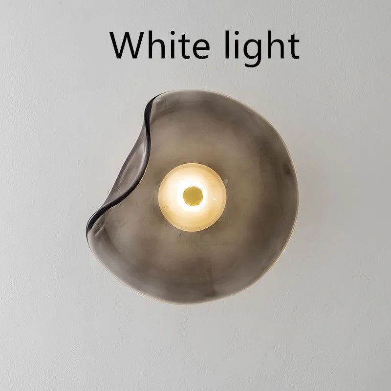 Round glass wall lamp for bedroom bedside in cognac, grey or light colour finishes.
