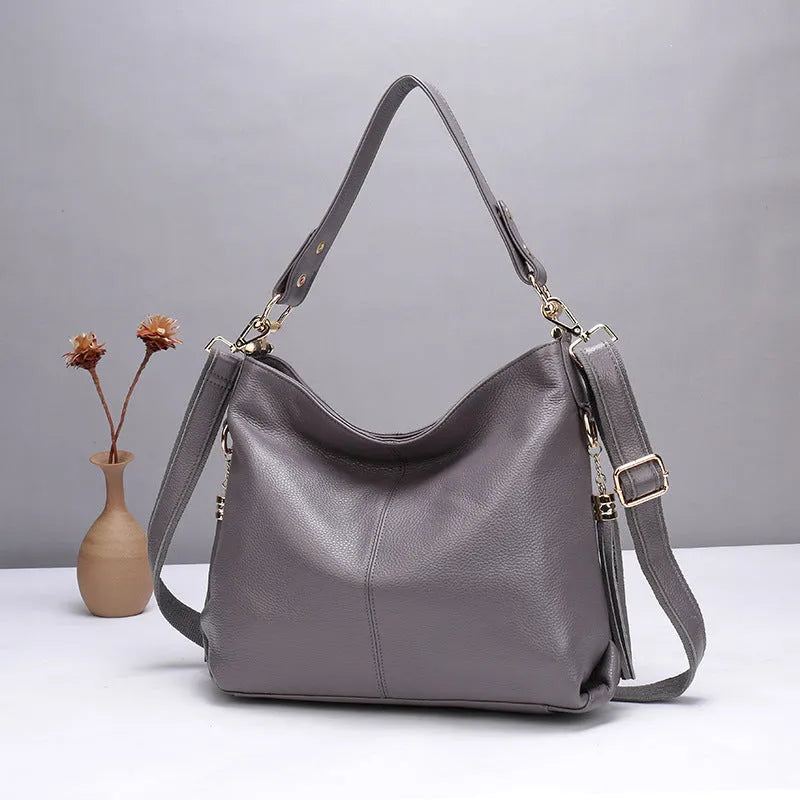 Genuine leather vertical square crossbody bag in black showing outer pocket and structured shape.