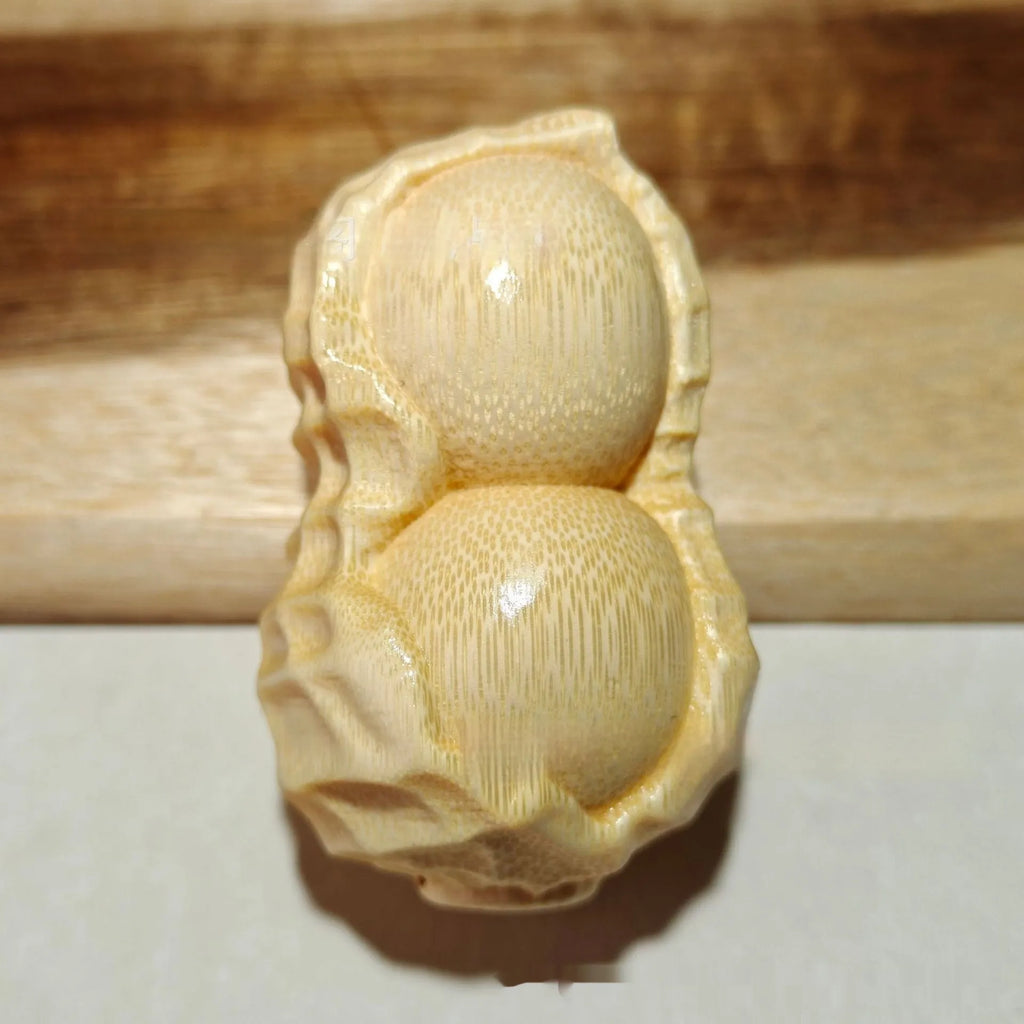 Solid natural bamboo hand-carved peanut ornament on a plain background.