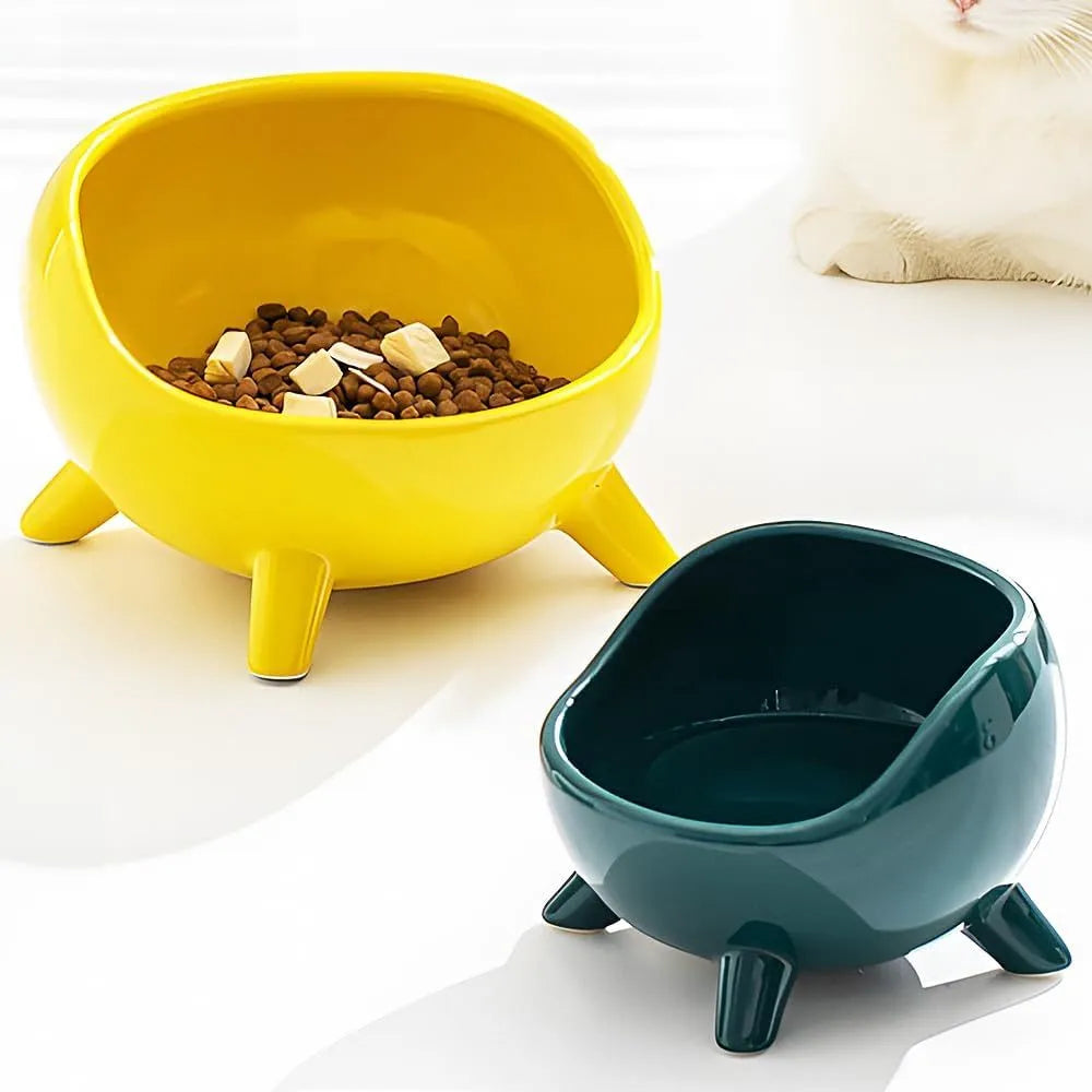 Green ceramic cat food bowl with four-leg stability base on wooden floor
