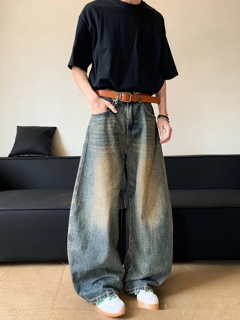 Man wearing retro blue distressed denim jeans with a slim-fit wide-leg cut.