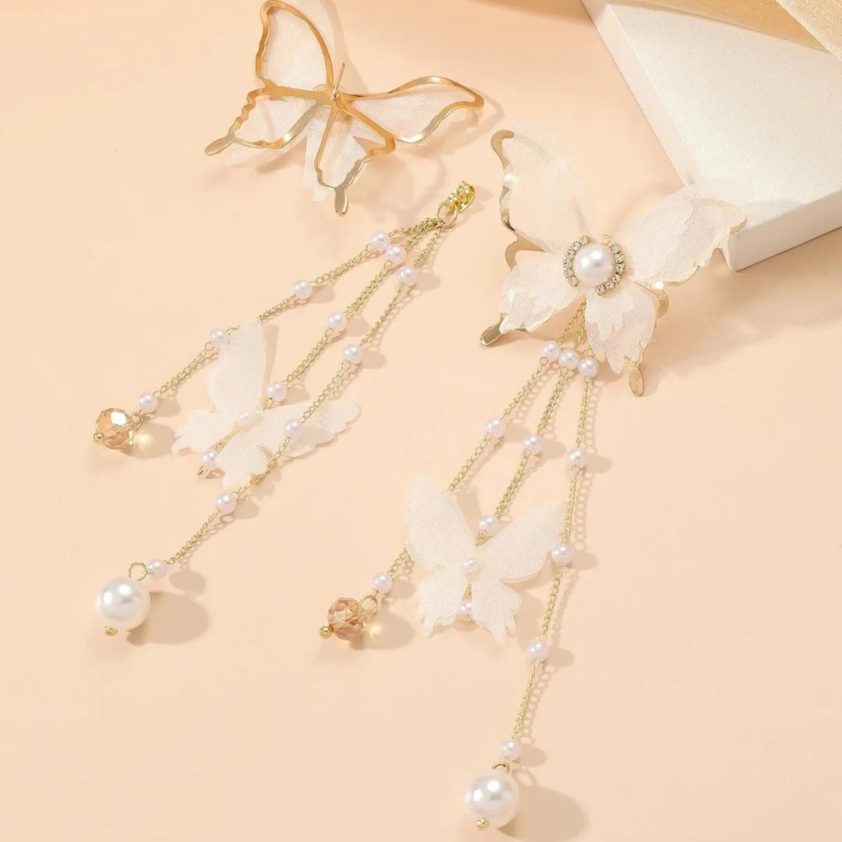 White butterfly-shaped women's earrings with dangling tassels, lace detail, pearl accents, and rhinestone sparkle.