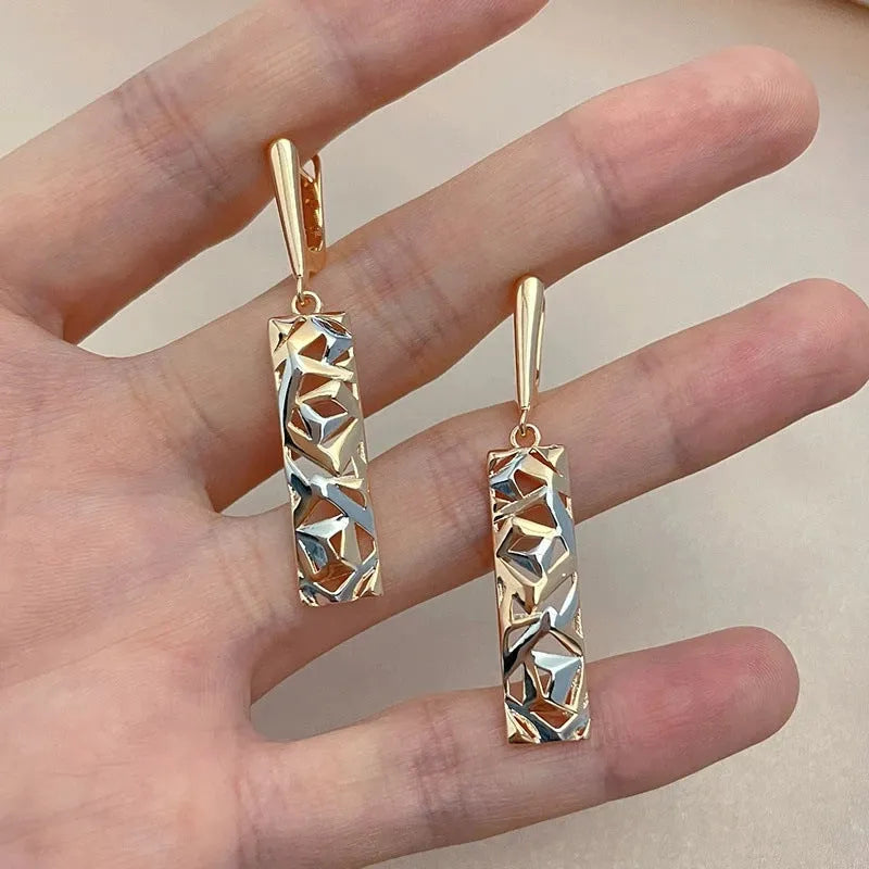 A pair of rectangular hollow stud earrings with a two-tone geometric design on a white background.