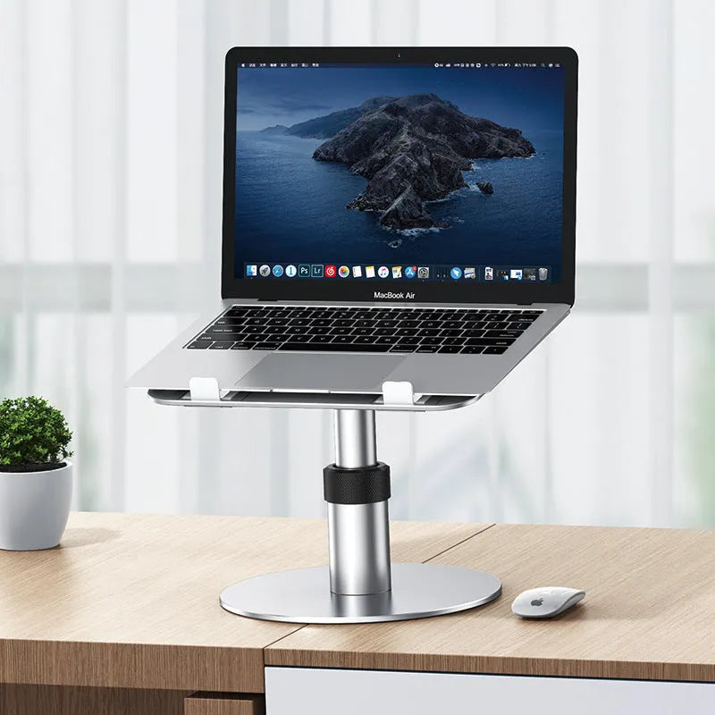 Silver adjustable aluminum laptop stand with non-slip pads on a desk next to a laptop.