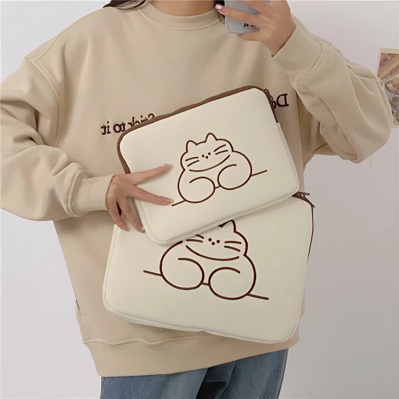 Embroidered fat cat design on a navy blue nylon tablet protective sleeve with a black zip.