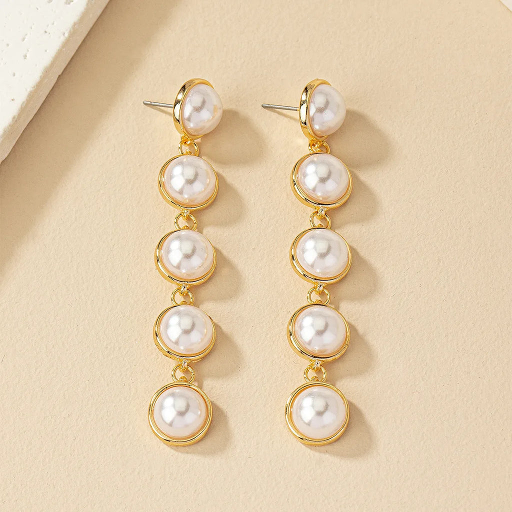 White metal drop tassel earrings with pearl water flow design on display