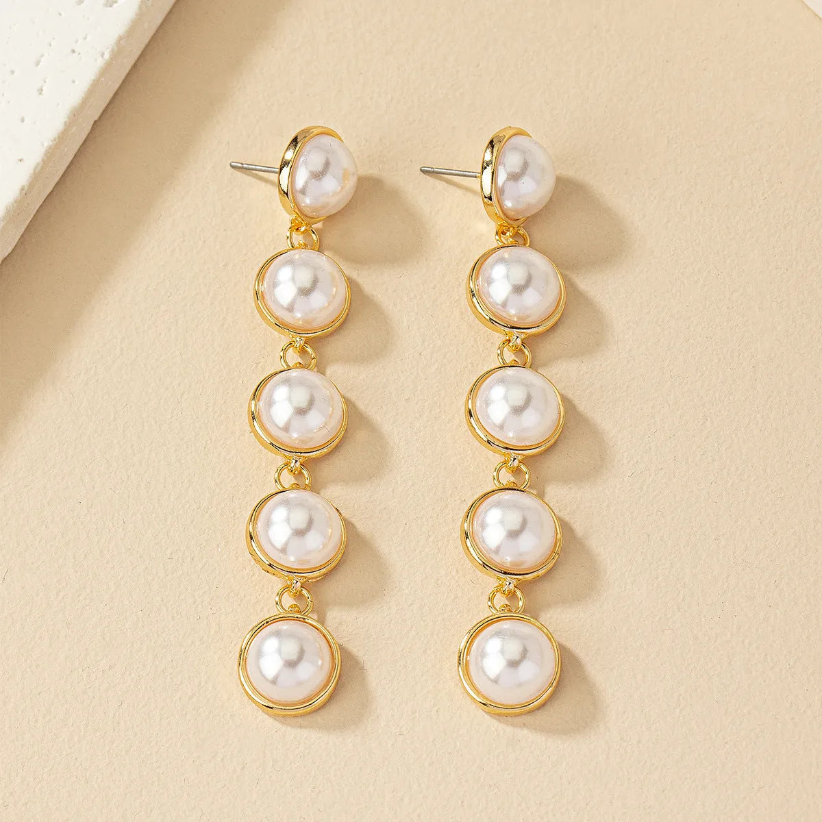 White metal drop tassel earrings with pearl water flow design on display