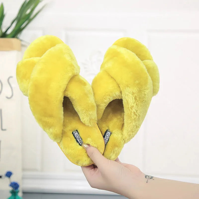 Women's black cross open-toe fur slippers with a patterned non-slip sole on a wooden floor