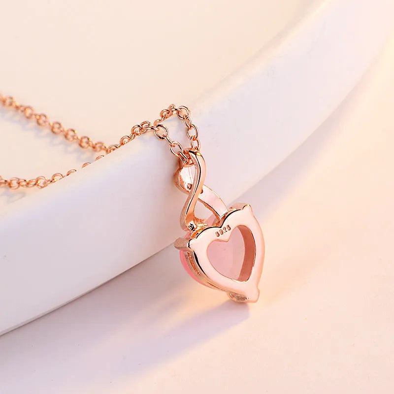 Rose gold cross chain necklace with a pink heart-shaped synthetic crystal pendant.