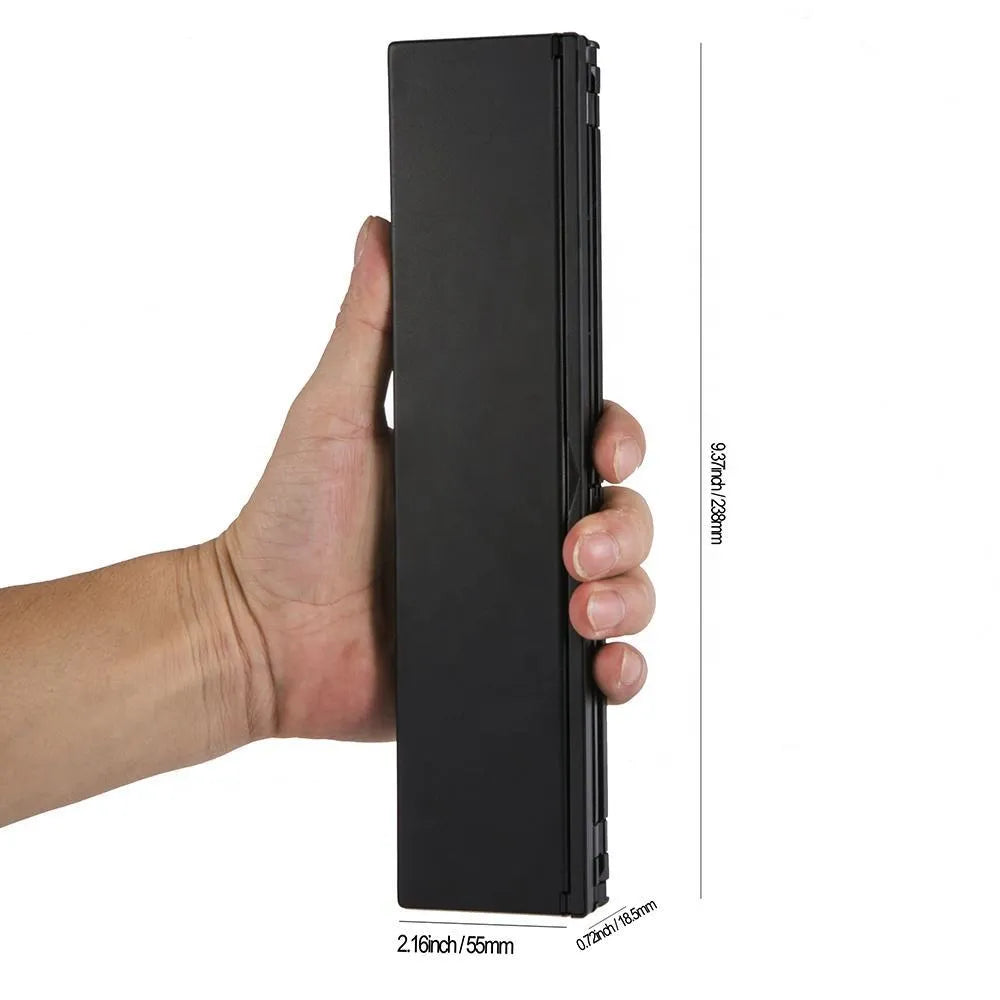 Black folding Bluetooth wireless keyboard next to tablet showing compact portable design