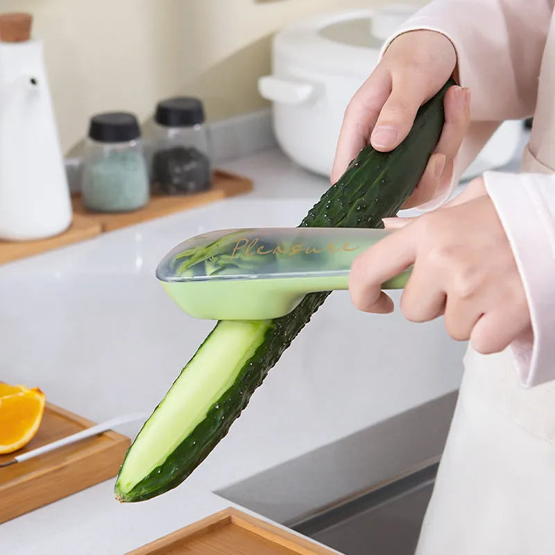 Dark green kitchen peeler with a stainless steel blade extended from its storage tube, showing the non-slip handle.