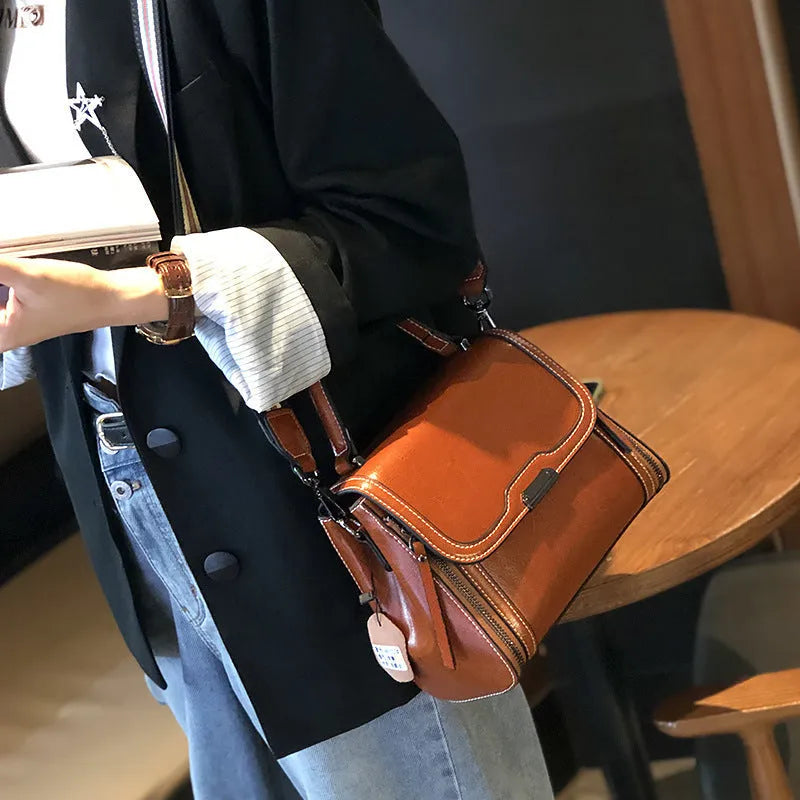 Women's brown genuine leather retro messenger bag with shoulder strap showing organised interior pockets.