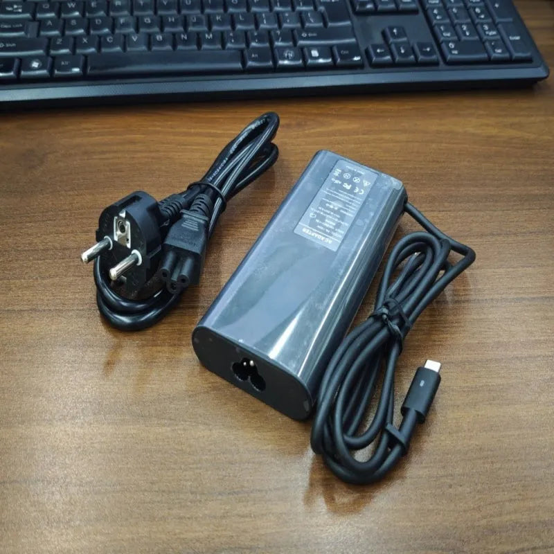 Black 65W Type-C laptop power adapter with multiple international power cords for UK US EU AU and ZA plugs.